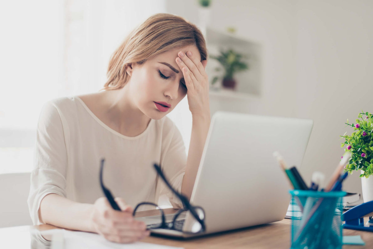 Stress-Symptome: Frau hat Kopfschmerzen am Arbeitsplatz