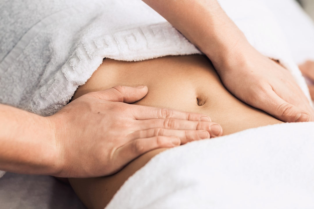 Hände massieren den Bauch einer Frau