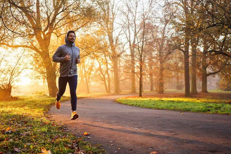 Mann geht bei Sonnenaufgang im Herbst im Wald joggen