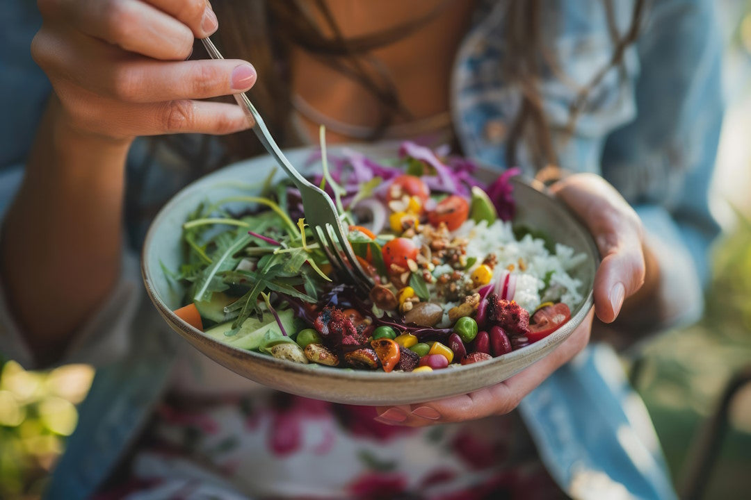 Frau sticht mit Gabel in Schüssel mit buntem Salat 