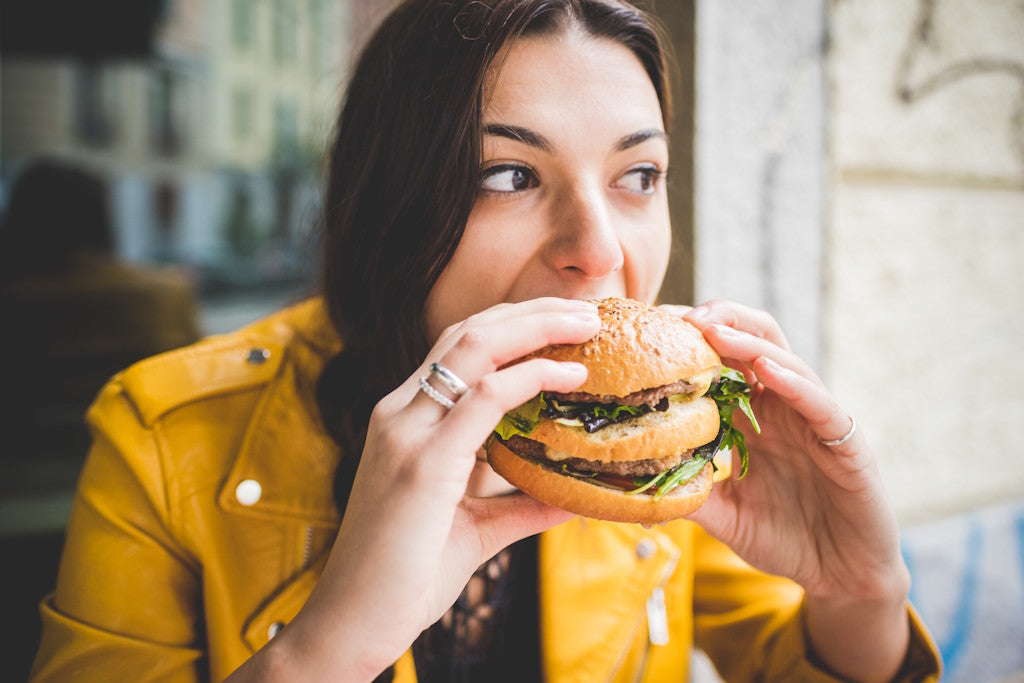 Frau sitzt im Restaurant und beißt in einen Burger
