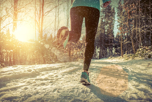 Frau geht im Winter bei Sonnenaufgang im Wald joggen