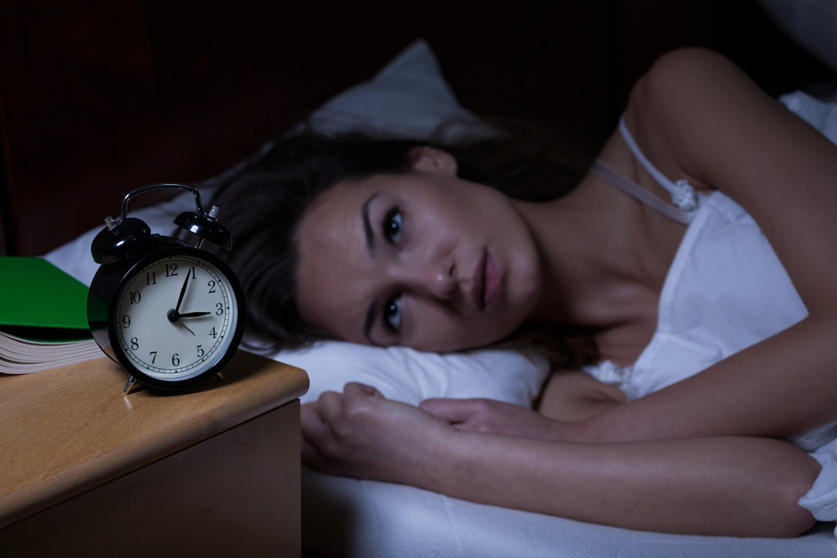 Schlafprobleme - schlaflose Frau schaut um 3 Uhr nachts auf Ihren Wecker