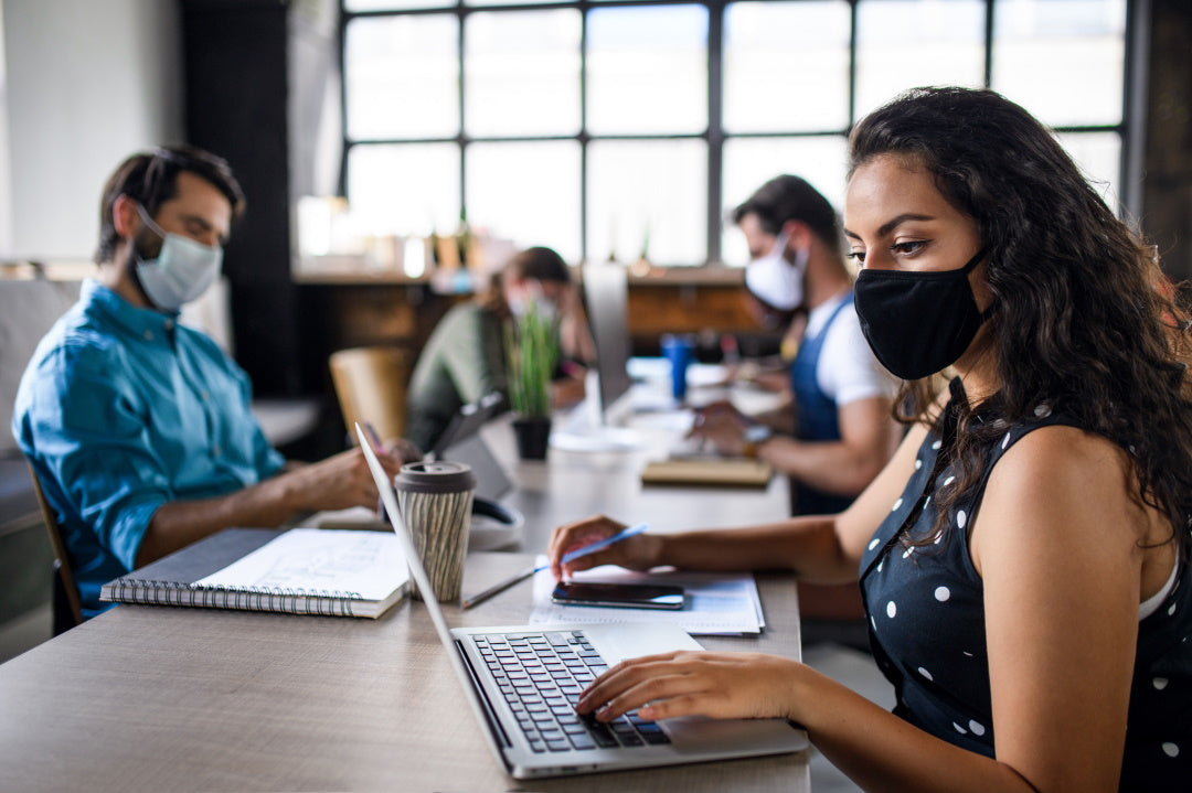 Junge Menschen arbeiten im Büro mit FFP2-Masken