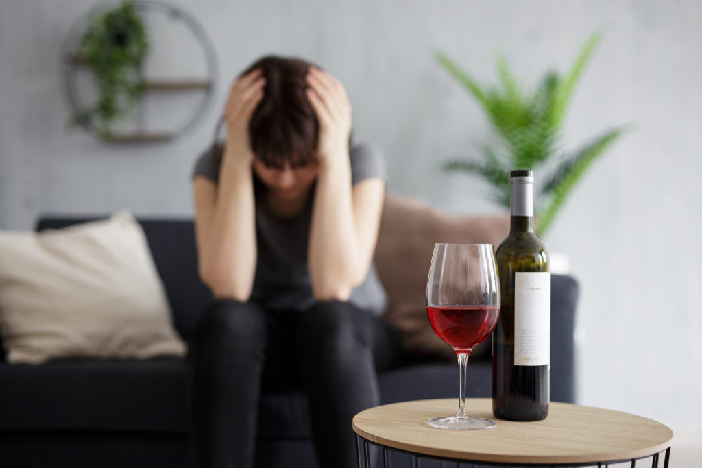 Frau hat Kopfschmerzen nach Rotwein-Trinken - Symptom der Histaminintoleranz