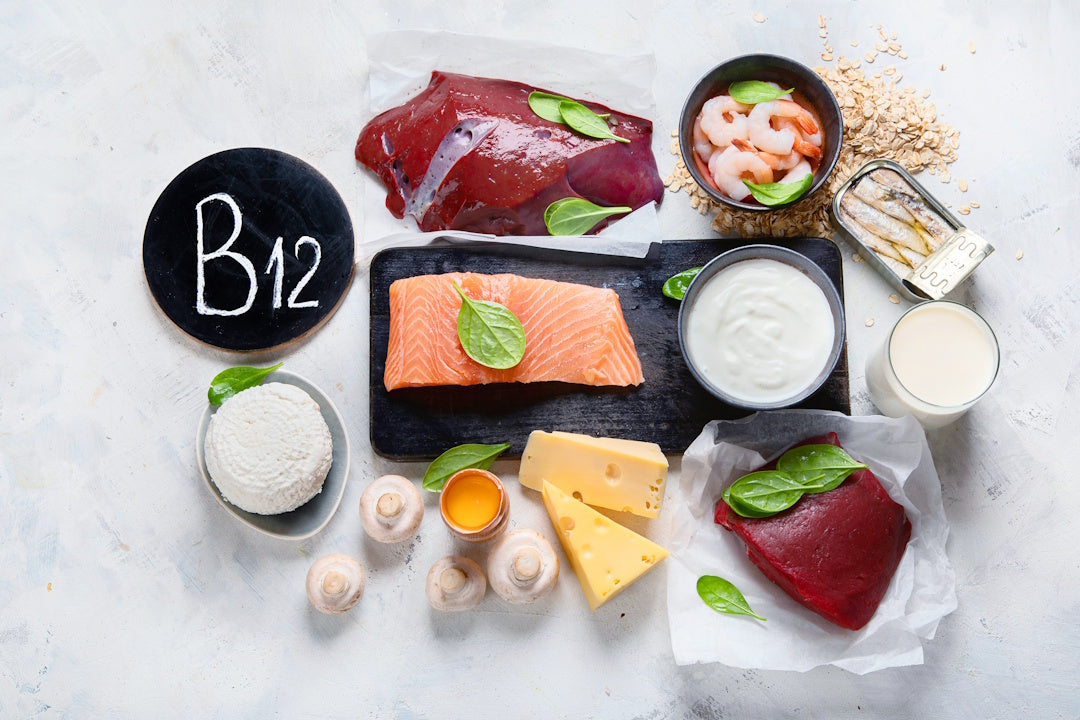 Vitamin-B12-reiche Lebensmittel auf einem weißen Steintisch: Fleisch, Fisch, Käse, Joghurt, Milch
