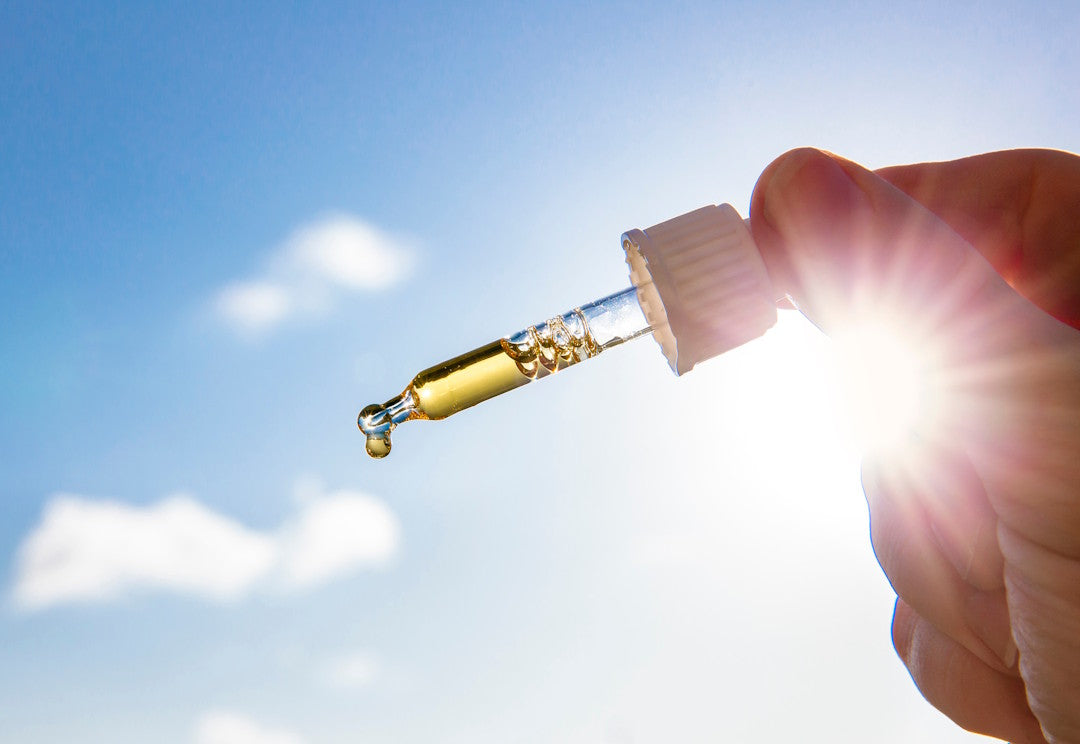 Vitamin-D-Tropfen in Pipette vor blauem Himmel