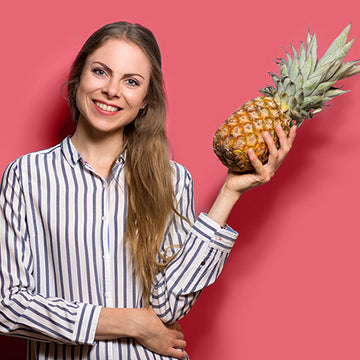 Bild der Ernährungsberaterin Mona Glock, die eine Ananas in der Hand hält